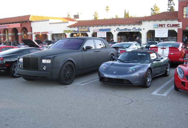 A Tesla electric car next to a Rolls Royce painted flat black